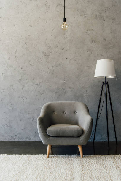istock Cozy grey armchair on white carpet and modern lamp in empty room 696170772