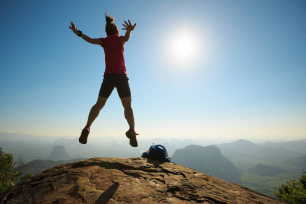 istock cheering woman backpacker jumping on sunrise mountain top 696171838