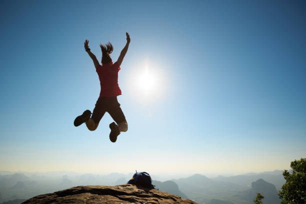 istock cheering woman backpacker jumping on sunrise mountain top 696173436