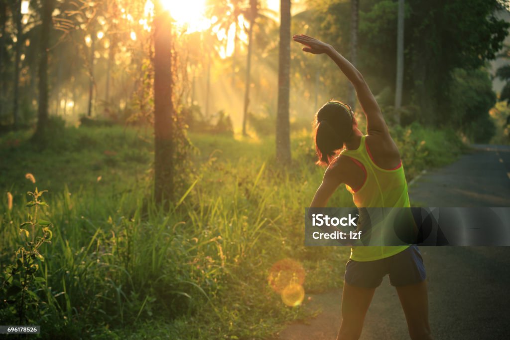 Junge weibliche Läufer Aufwärmen vor laufen am Morgen Waldweg - Lizenzfrei Dehnen Stock-Foto