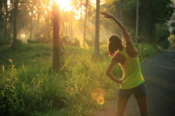 young female runner warming up before running at morning forest trail - morning imagens e fotografias de stock