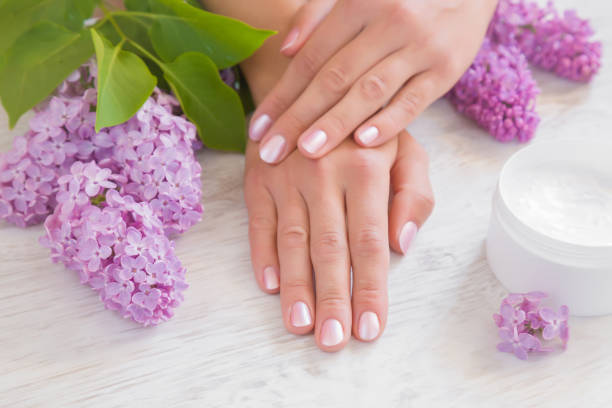 Hands moisturizing cream cares about woman's hands skin. Manicure beauty salon. Spring and summer gentle atmosphere with fresh and fragrant purple lilac flowers on the wooden table. Hands moisturizing cream cares about woman's hands skin. Manicure beauty salon. Spring and summer gentle atmosphere with fresh and fragrant purple lilac flowers on the wooden table. yellow nail polish stock pictures, royalty-free photos & images