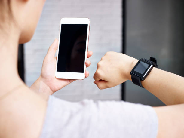 istock young woman using cellphone and smart watch 696182448