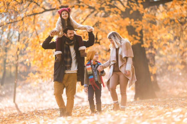 istock Happy family having fun while walking during autumn day through the park. 696183218