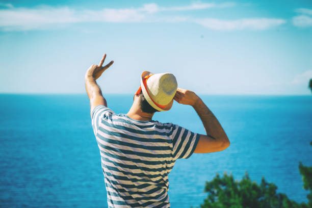istock Modern man holding peace sign on the beach. 696183262