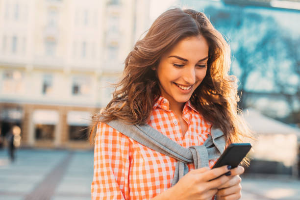 istock Beautiful woman texting outdoors 696183522