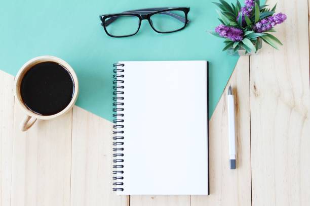 istock Top view image of open notebook with blank pages and coffee cup on wooden background, ready for adding or mock up 696186266
