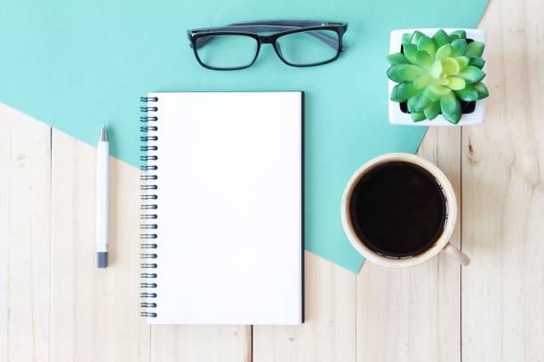 istock Top view image of open notebook with blank pages and coffee cup on wooden background, ready for adding or mock up 696186268