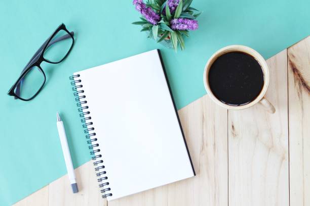 istock Top view image of open notebook with blank pages and coffee cup on wooden background, ready for adding or mock up 696186270