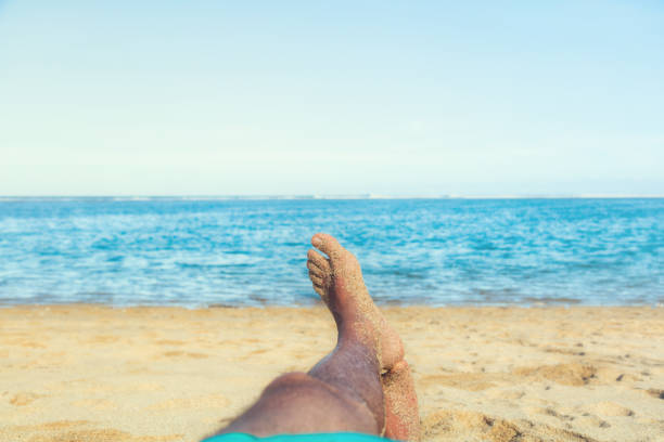 Man enjoying at the beach - focus is on feet.