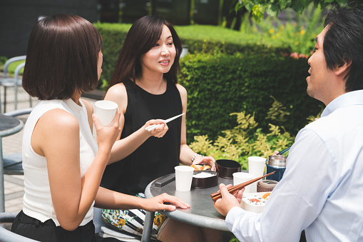 Three japanese office workers having lunch together outdoor