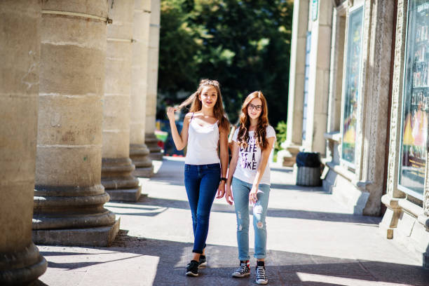 istock Two young girls having fun standing next to the columns. 696195130