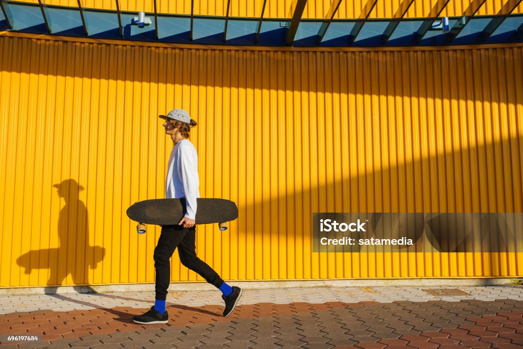 Hipster teenager walking with longboard Young skater boy walking outdoors with longboard Skateboarding Stock Photo