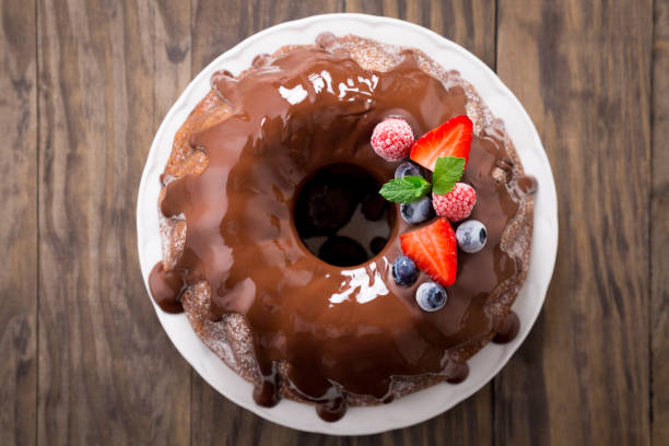 Chocolate bundt cake with berries Chocolate bundt cake with melted chocolate and frozen berries. Top view sprinkling powdered sugar stock pictures, royalty-free photos & images