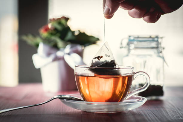 Someone preparing tea Putting tea bag into glass cup full of hot water black tea stock pictures, royalty-free photos & images