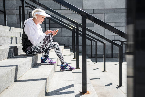 istock Concentrated aged lady messaging through her cellphone on stone steps 696206432