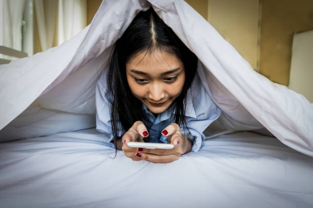 istock Asian woman using a smart phone in the bedroom. 696209572