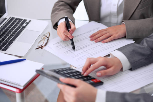 Two female accountants counting on calculator income for tax form completion hands closeup. Internal Revenue Service inspector checking financial document. Planning budget, audit concept. dos contadores mujer contando con ingresos de calculadora para impuestos forman closeup de las manos de terminación. inspector de servicio de impuestos interno comprobación de documento financiero. planificación presupuesto, concepto de auditoría