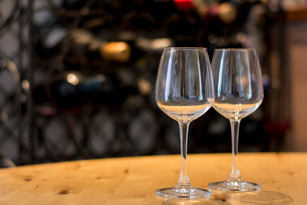 istock Empty wine glasses on a wooden plank with defocused bottles in background 696240570