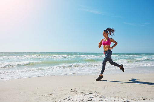 Shot of an attractive young woman working out on the beach