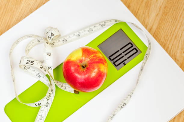 istock Apple with measuring tape close up on digital scale 696247616