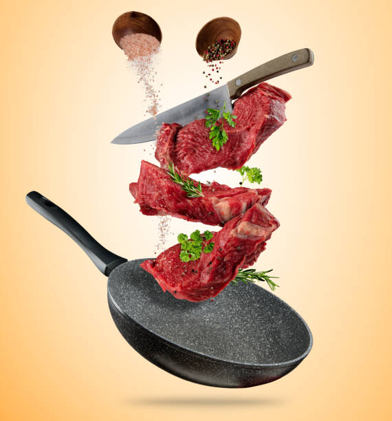 istock Flying raw steaks with cooking ingredients from pan 696248312