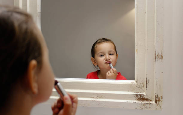 istock Little girl applying makeup in mirror 696257254