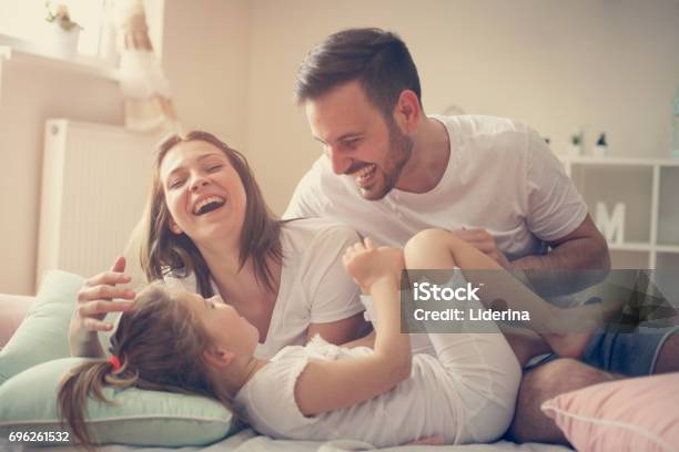 親のベッドの上の彼らの幼い娘を楽しんでします朝の時間を過ごす家族 - 家族のストックフォトや画像を多数ご用意 - 家族, ベッド, 家庭生活