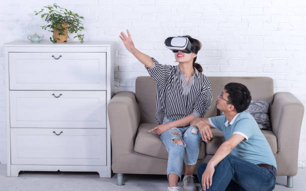 istock Young Asian couple experiencing virtual reality technology at home 696262276