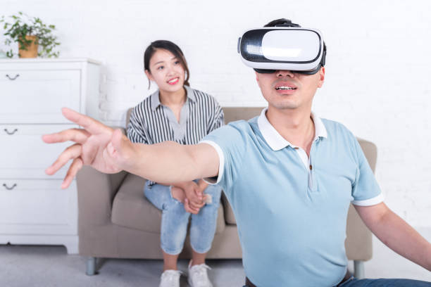 istock Young Asian couple experiencing virtual reality technology at home 696264664