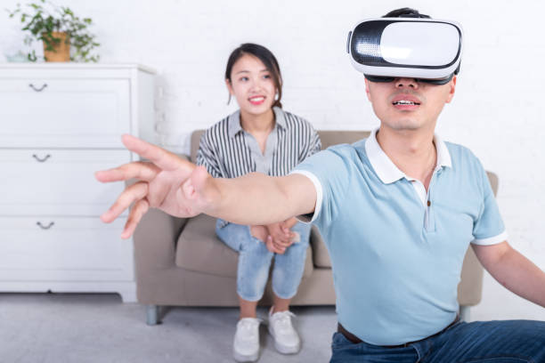 istock Young Asian couple experiencing virtual reality technology at home 696264834
