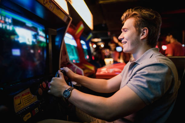 Amusement Arcade Gaming Young male playing driving arcade games at an amusement arcade. arcade photos stock pictures, royalty-free photos & images