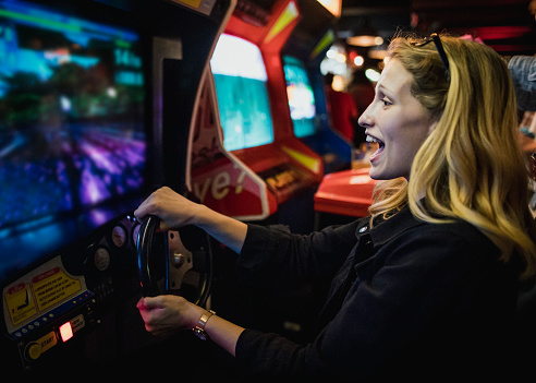 Young female playing a driving arcade game.