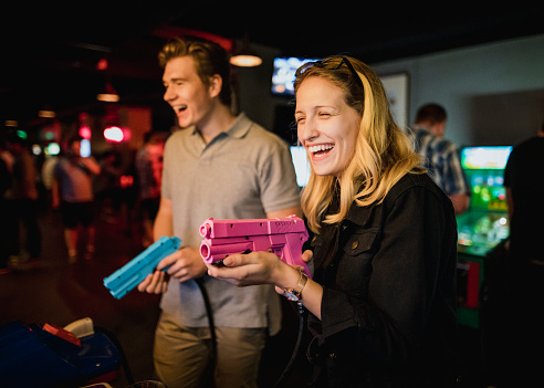 Young couple playing arcade games at a bar.