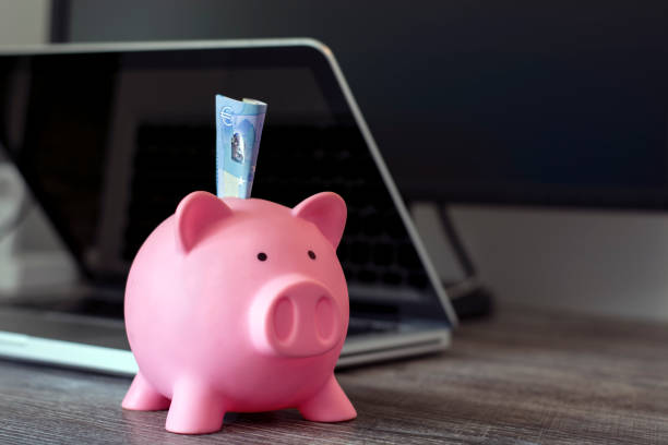 porquinho mealheiro com laptop e euro moeda na mesa dentro de casa - piggy bank currency savings finance - fotografias e filmes do acervo