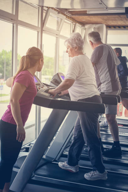 istock Personal trainer exercise helps elderly couple. Senior couple on the jogging machine. 696274688