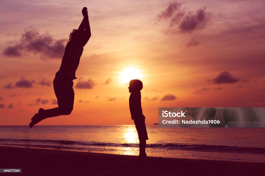 happy father and son jumping at sunset beach happy father and son jumping at sunset beach, vacation concept Adult Stock Photo
