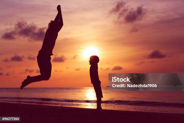 Happy Father And Son Jumping At Sunset Beach Stock Photo - Download Image Now - Adult, Baby - Human Age, Baby Boys