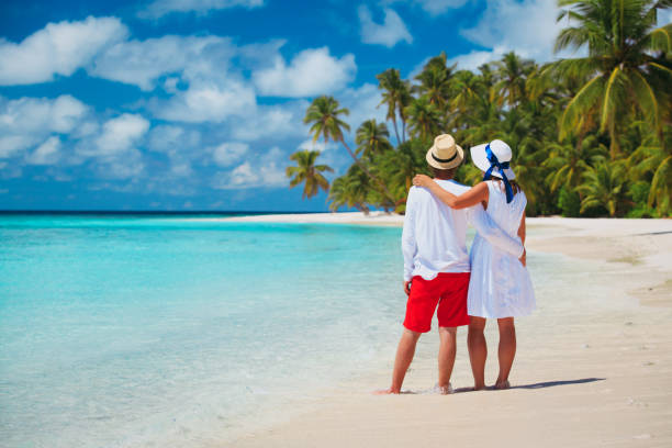 istock happy loving couple walking on beach 696277664