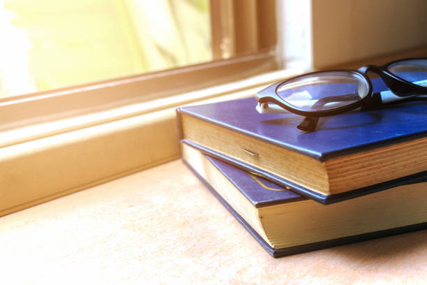 istock workplace with text space, book and spectacles on wood table with soft-focus and over light in the background 696281112