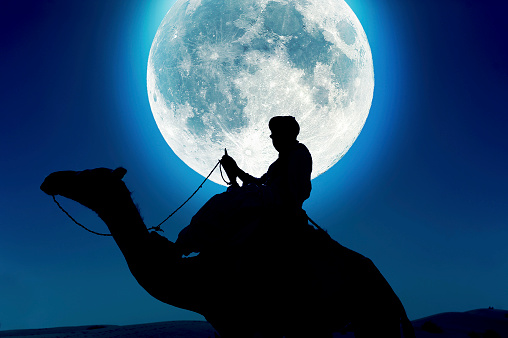 Tuareg with camel in front of full moon