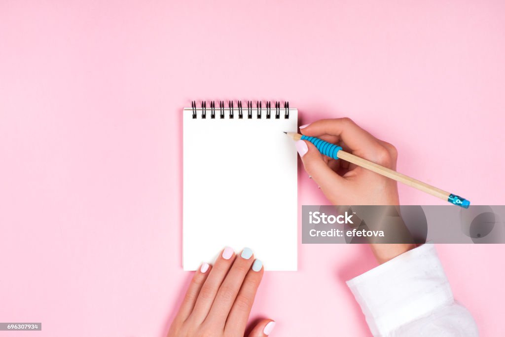 Spiral notepad with pencil as mockup for design Woman's hands with perfect manicure holding pencil and spiral notepad as mockup for your design. Pink background, flat lay style. To Do List Stock Photo