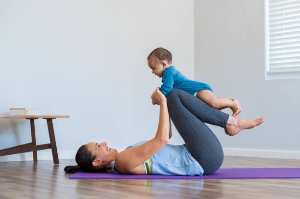 Mother and little son exercising Mother with cute baby doing gymnastic exercise at home. Athletic mother holding little child on leg while doing exercise on yoga mat. Healthy mother playing and doing yoga with little boy. relaxation lying on back women enjoyment stock pictures, royalty-free photos & images