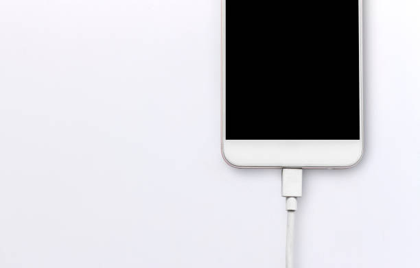 istock closeup smartphone and charger on white table. soft-focus and over light in the background 696314632