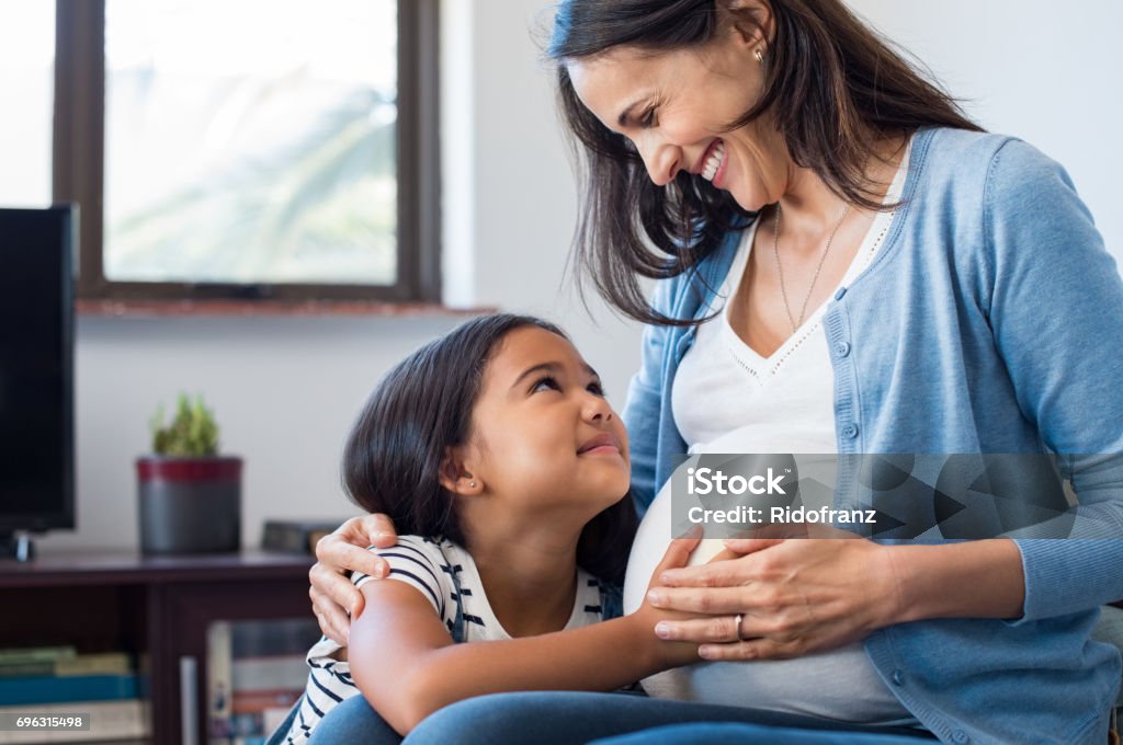 Filha, tocando o ventre de sua mãe grávida - Foto de stock de Grávida royalty-free