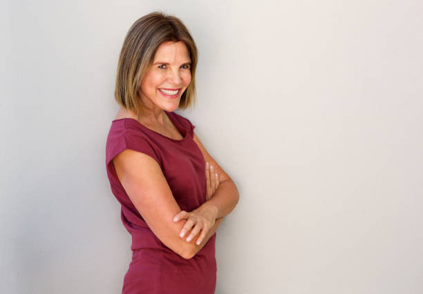 istock smiling middle age woman against white wall 696318282