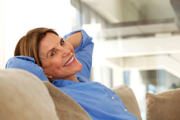 istock smiling older woman sitting on sofa at home 696318412