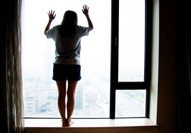 istock Pensive woman looking out the window 696321800