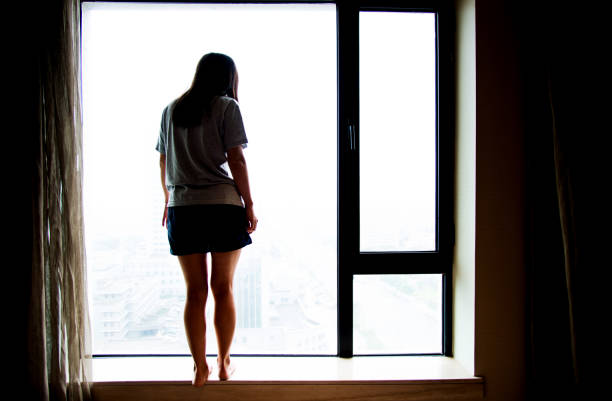 istock Pensive woman looking out the window 696321868