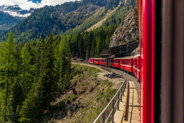 Red train slowly climbing to the Bernina Pass in the Swiss Alps - 2